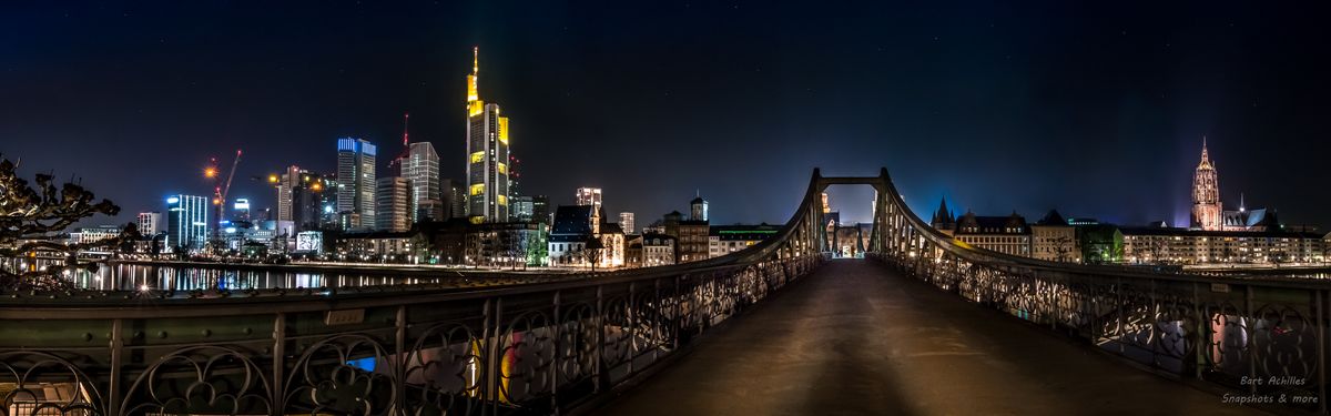 This is the Skyline of Frankfurt am Main and the bridge is called Eiserner Steg. The bridge has been build in 1868, crosses the river Main and it's only for pedestrian. This is a panorama  of 3 pictures.